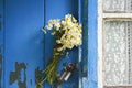 Bouquet of daisies stuck in the handle of the closed door of the old wooden house