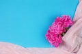 Bouquet of dark pink peony flowers close up and pink fabric on blue background with copy space. Royalty Free Stock Photo