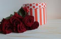 A bouquet of red roses is on the table with a gift box. Royalty Free Stock Photo