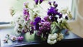 A bouquet of dried violet, pink and white wildflowers lying on the book. Bright flowers lit by sunlight. Soft selective focus,