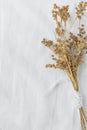 Bouquet of Dry Beige Brown Flowers Tied with Silk Ribbon on White Linen Fabric Background. Japanese Style. Easter Mother`s Day. Royalty Free Stock Photo