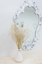 A bouquet of dry wildflowers stands in a white vase on a boudoir table by a vintage mirror Royalty Free Stock Photo