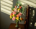 Bouquet of fake artificial roses in a vase set on a wooden chair with louvered sunlight. Royalty Free Stock Photo