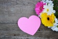 Bouquet of flowers with pink paper heart on wood