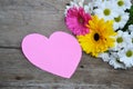 Bouquet of flowers with pink paper heart on wood