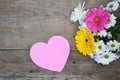 Bouquet of flowers with pink paper heart on wood