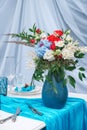 Bouquet of flowers in a blue vase standing on a banquet table Royalty Free Stock Photo