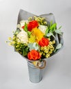 A bouquet of flowers is in a bucket of galvanized iron on a light background