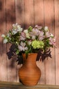 A bouquet of flowers in a clay jug on the background of the old wall at sunset summer sun. Moscow region, Russia. Royalty Free Stock Photo