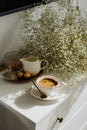 A bouquet of flowers, a cup of tea or coffee with milk and sweets on the table. Feels like home comfort and minimalism. aesthetic. Royalty Free Stock Photo