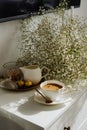 A bouquet of flowers, a cup of tea or coffee with milk and sweets on the table. Feels like home comfort and minimalism. aesthetic. Royalty Free Stock Photo