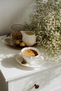 A bouquet of flowers, a cup of tea or coffee with milk and sweets on the table. Feels like home comfort and minimalism. aesthetic. Royalty Free Stock Photo