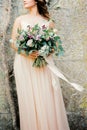Bouquet of flowers in the hands of a bride in a beige dress