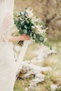 Bouquet of flowers in the hands of bride in a white dress with a veil. Close up Royalty Free Stock Photo