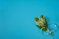 A bouquet of flowers and leaves of the may Lily of the valley Convallaria majalis with a gray bow on a light blue background. Royalty Free Stock Photo