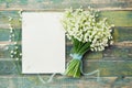 Bouquet of flowers lily of the valley and empty paper sheet on rustic table from above, beautiful vintage card, top view Royalty Free Stock Photo
