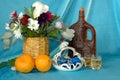 A bouquet of flowers, oranges, a bottle of wine, glasses, a vase