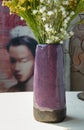 Bouquet of flowers in Purple ceramic vase on white textured table cloth in front of Classic chinese poster movie frame