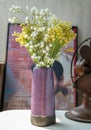 Bouquet of flowers in Purple ceramic vase on white textured table cloth in front of Classic chinese poster movie frame