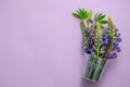 Bouquet of flowers purple lupines in small decorative silver bucket on purple background with space for text