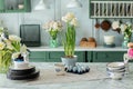 Bouquet of flowers in vase and porcelain plates on table. Home interior with easter decor. Spring flowers and Utensil in kitchen.