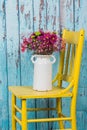 Bouquet of flowers in vintage vase sitting on yellow chair