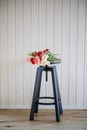 A bouquet of flowers on wooden stool against white background wall. Royalty Free Stock Photo