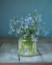 Bouquet of forget-me-nots in a glass corrugated jar on a turquoise table