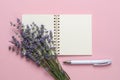 Bouquet of fragrant blooming lavender on a blank paper notepad and white ballpoint pen over a textural pink background. Summer and