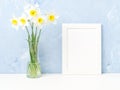 Bouquet of fresh flowers, white frame on table, opposite blue textured concrete wall. Empty space for text. Mock up. Royalty Free Stock Photo