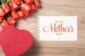 Bouquet of fresh pink red roses with gift on wooden background. Floral romantic arrangement with card text Happy Mother's Day Royalty Free Stock Photo