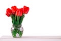 Bouquet of fresh red tulips in glass vase on wooden table, isolated on white Royalty Free Stock Photo