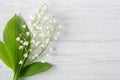 Bouquet of fresh spring Lily of the valley flowers with green leaves on wooden background