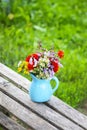 Bouquet of fresh summer flowers in a blue ceramics vase on wooden bench Royalty Free Stock Photo