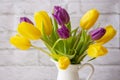 Bouquet of fresh tulips close-up. Yellow purple two-colored flowers tulips in a bouquet in a white jug, horizontal background Royalty Free Stock Photo
