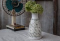 Bouquet of green flowers in White handmade ceramic vase bottle shape and Vintage fan on white textured table cloth with old cement Royalty Free Stock Photo