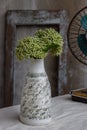 Bouquet of green flowers in White handmade ceramic vase bottle shape and Vintage fan on white textured table cloth with old cement Royalty Free Stock Photo