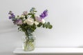 Bouquet of hackelia velutina, purple and white roses, small tea roses, matthiola incana, blue iris in glass vase is on the white Royalty Free Stock Photo