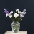 Bouquet of hackelia velutina, purple and white roses, small tea roses, matthiola incana, blue iris in glass vase opposite on black Royalty Free Stock Photo