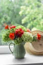 Bouquet of hydrangeas, dahlias, roses in a ceramic jug and a straw hat on the window against the background of a summer garden Royalty Free Stock Photo