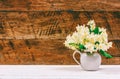 Bouquet of Jasmine flowers in a jug on a white table on a brown wooden retro background Royalty Free Stock Photo