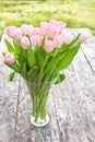 Bouquet of light pink tulips on the oak brown table in a clear g Royalty Free Stock Photo