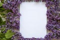 A bouquet of lilac flowers with notebook on a white wooden background. Mothers Day. Copy space. From above, flat lay. Royalty Free Stock Photo