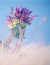 A bouquet of lilac flowers of wild sage in the hands of a girl among grass feather grass swaying in the wind.