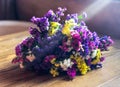 Bouquet of lilac, yellow, white and purple flowers on wooden table in sunlight. Potpourri close-up. Copy space