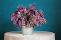 A bouquet of lilacs in a bucket on a blue background.