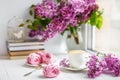 Bouquet of lilacs, cup of coffee, homemade marshmallow and stack of books on window sill Romantic spring morning