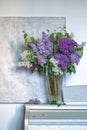 a bouquet of lilacs in a transparent vase on a light textured background. vertical image of lilac, violet and white Royalty Free Stock Photo