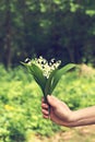 A bouquet of lilies of the valley in a woman's hand.