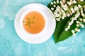 Bouquet of lily of the valley and cup of chamomile tea Royalty Free Stock Photo